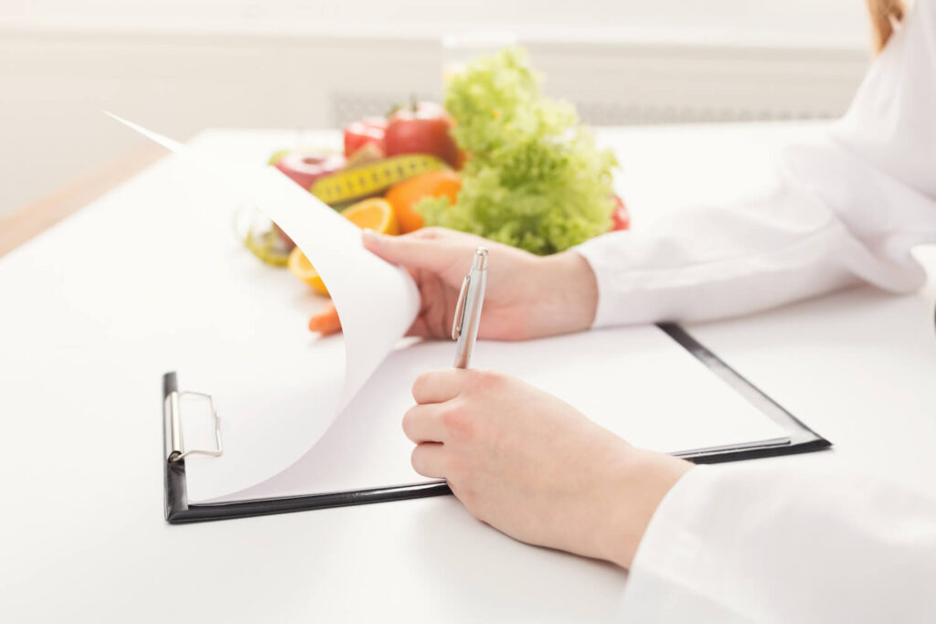 Nutritionist signing paper with healthy food on table