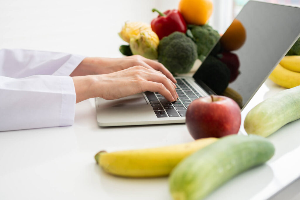 Nutritionist working on laptop with healthy food on table